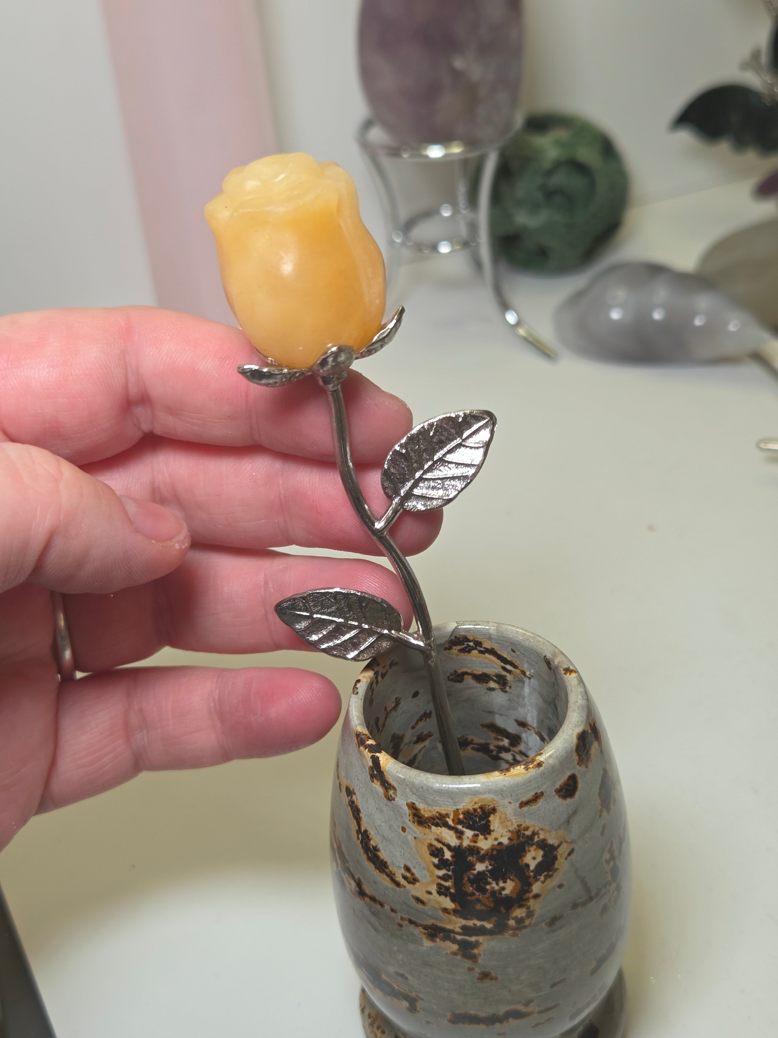 Orange calcite crystal rose carving on a stem