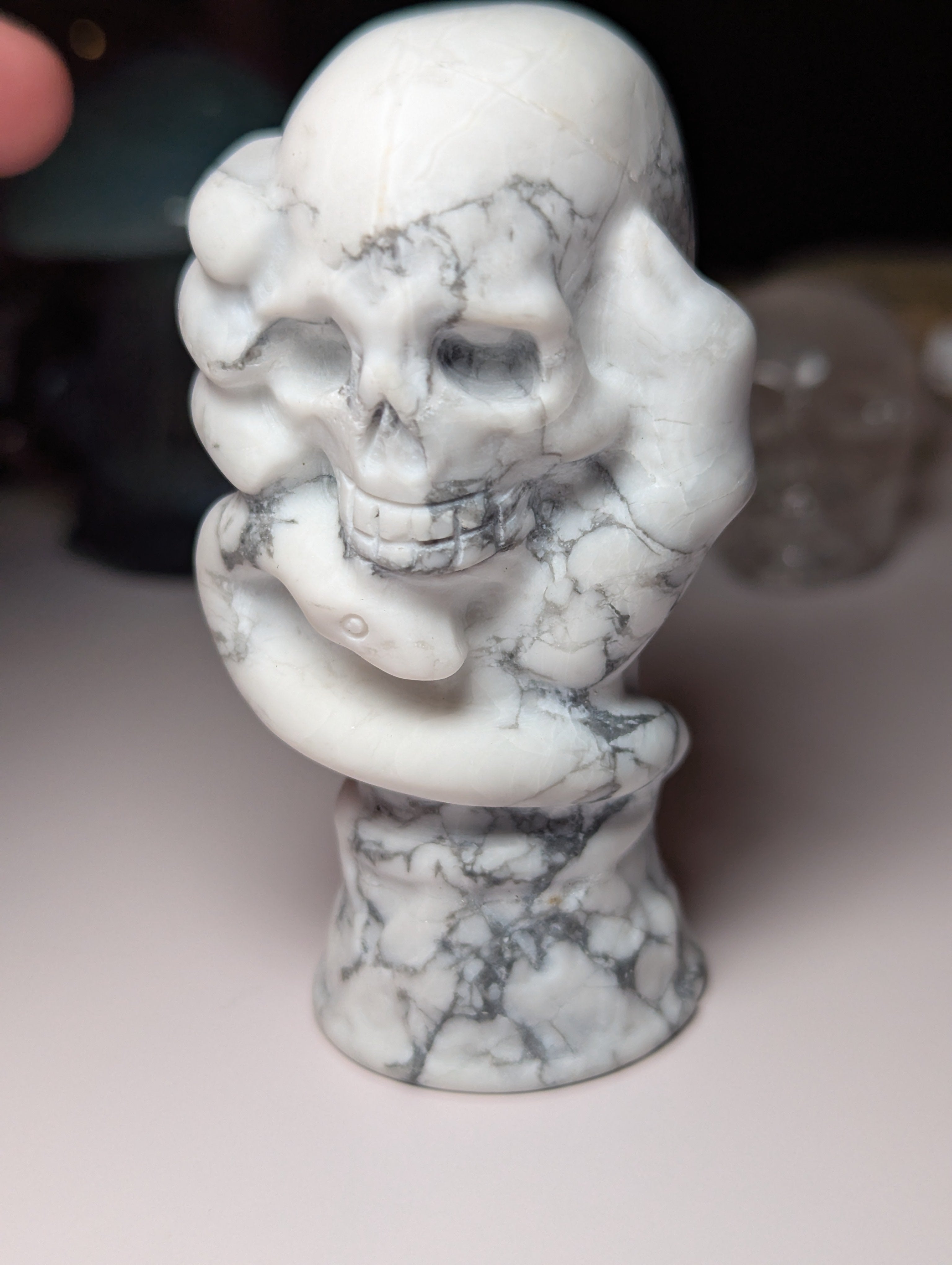 Howelite crystal hand holding skull carving