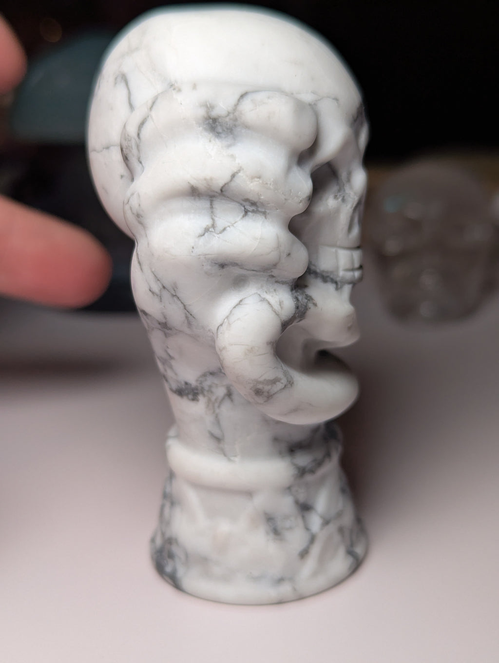 Howelite crystal hand holding skull carving