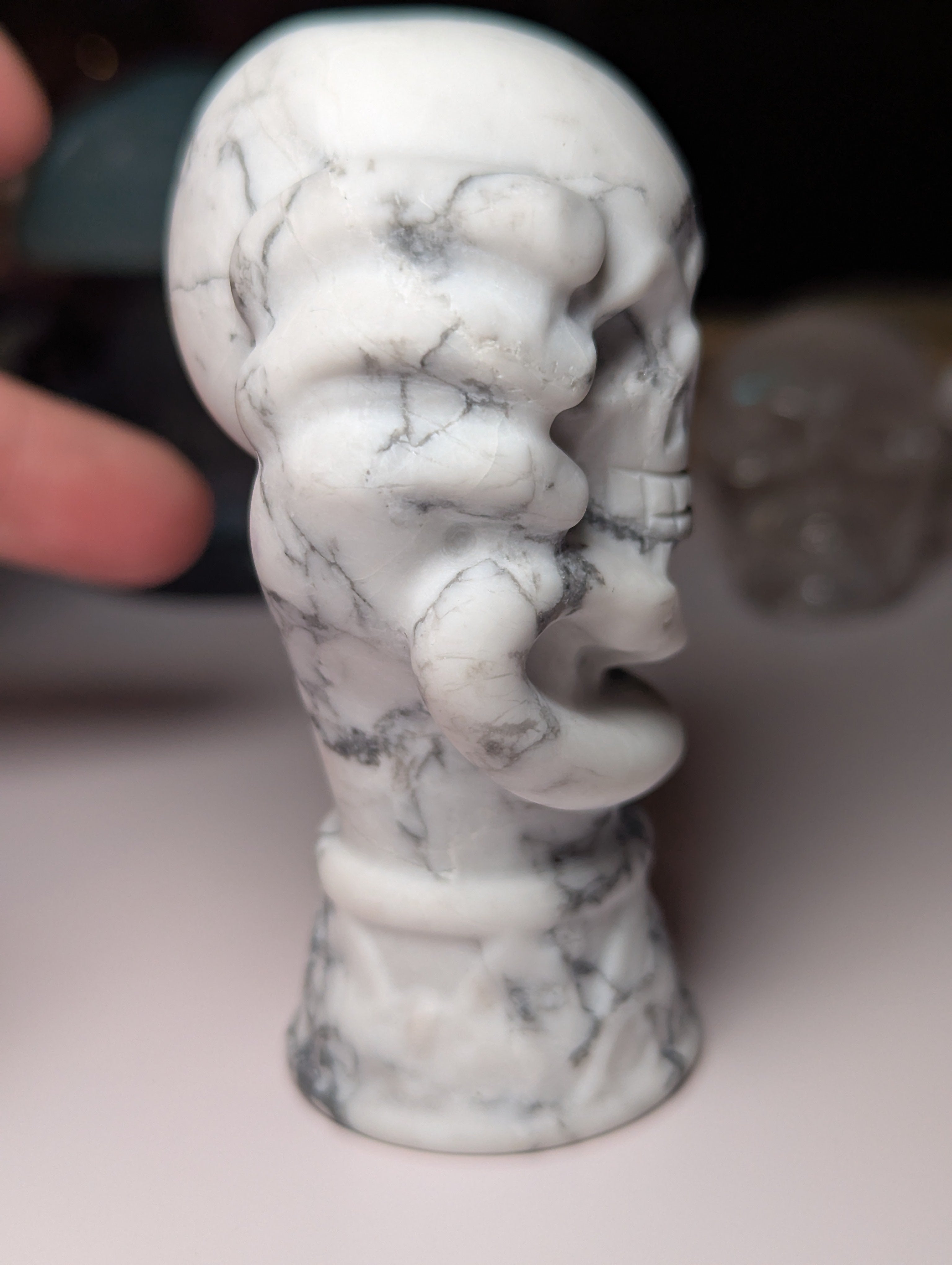 Howelite crystal hand holding skull carving