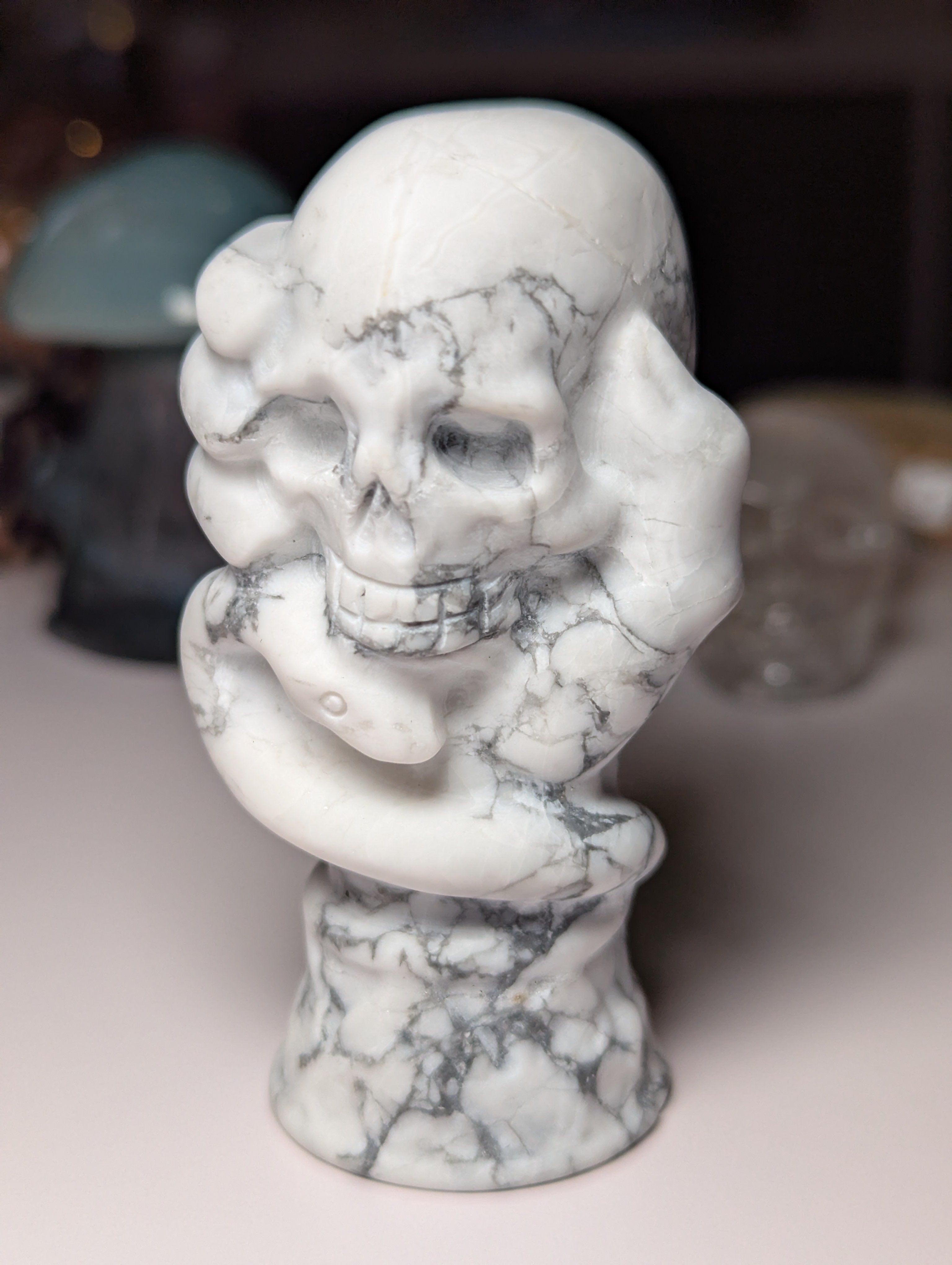 Howelite crystal hand holding skull carving
