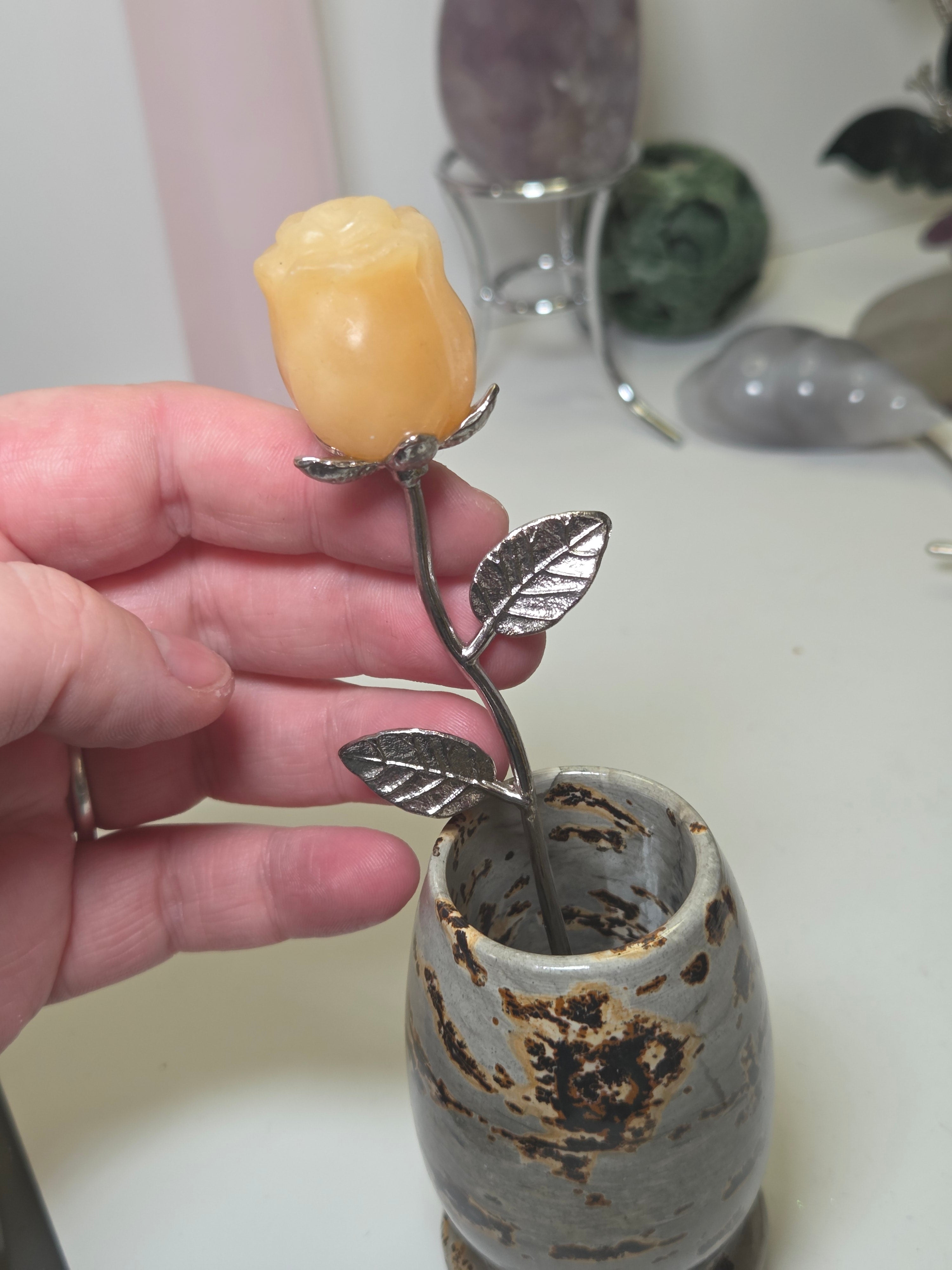 Orange calcite crystal rose carving on a stem